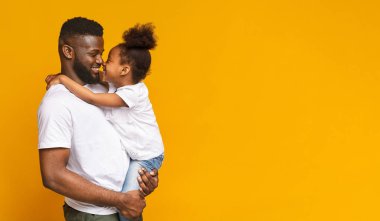 Mutlu bir aile. Babası, boş alan ile turuncu panorama arka plan ile burun dokunmadan sevimli küçük Afrikalı kız