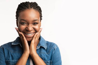 Ortodonti Konsepti. Beyaz arka plandaki kameraya gülümseyen, el pençe divan duran neşeli siyah kız. Stüdyo Çekimi