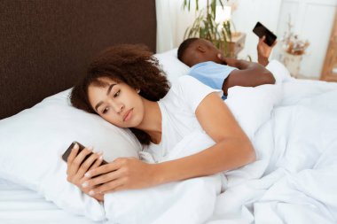 Yatakta tatil günü, alet bağımlılığı ve sosyal medyadan kaynaklanan birkaç sorun. Binlerce yıldır meşgul olan Afro-Amerikan karı-koca telefonlara baktılar ve yatak odasının içinde uzayı kopyaladılar.