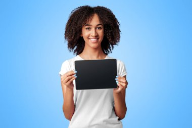 Yeni mobil uygulama, güzel web sitesi, çevrimiçi alışveriş, evde eğitim veya metin için kopyalama alanı. Gülümseyen Afrikalı Amerikalı kadın elinde mor arka planda izole edilmiş, boş ekranlı dijital tablet tutuyor.