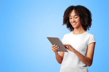 İnternette çalışmak, flört etmek ve yalnızlık üzerine sohbet etmek. İnternette tabletle sörf yapan ve mor arka planda izole edilmiş mesaj yazan kıvırcık saçlı neşeli Afro-Amerikalı bayan.