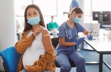 Covid-19 Aşı Konsepti. Corona virüsü aşısı olduktan sonra kolunda yapıştırıcı bandaj olan, cerrahi maskeli bir kadının portresi. Antiviral Enjeksiyon