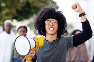 Karışık ırk adamıyla megafonlu önde gelen uluslararası protestocu grubu, yumruklarını kaldırıp sloganlar atıyorlar. Hoparlörlü grevcilerin lideri hükümete bağırıyor