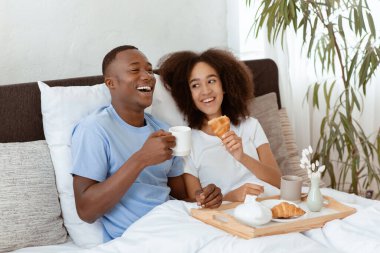 Aşık bir çift, balayı sırasında yatakta kahvaltı yapıyor ve dinleniyor. Kahkahalarla gülen Afro-Amerikan bir aile kahve ve yemek ile yatak odasının iç kısımlarında yemek yiyip rahatlıyorlar.