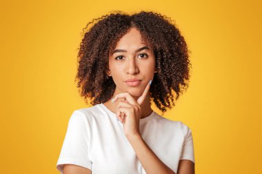 Güzel, güzel, tatlı bir bayan, genç model çene dokunuşu, karar verme, sorunları çözme ikilemi. Düşünceli Afro-Amerikan kadın, hakkında düşünüyor, sarı arka planda izole, serbest alan