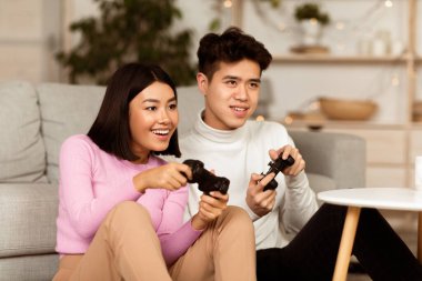 Mutlu Koreli çift hafta sonları evdeki koltukta oturup bilgisayar oyunu oynuyorlar. Çinli erkek arkadaş ve kız arkadaş video oyunları oynuyorlar. Aile Hafta Sonu Eğlencesi, Bilgisayar Oyunları Konsepti