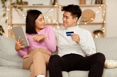 Hafta sonları evdeki koltukta oturan Koreli çift dijital tablet ve kredi kartı satın alarak internetten alışveriş yapıyor. Mobil Bankacılık, E-Ticaret ve Mutlu Müşteriler Konsepti