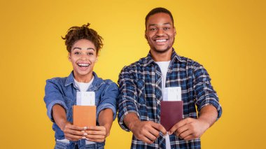 Tatil kavramı. Neşeli Siyah Turistler, Sarı Stüdyo Arkaplanının Üzerinde Duran Kamera Pozisyonuna Seyahat Biletleri Gösteriyor. Seyahat, Tatil Gezisi ve Turizm Keyfi