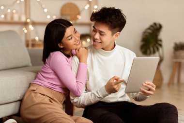 Asyalı Milenyum Çifti Dijital Tablet Bilgisayar Kullanarak İnternet Sörfü Çevrimiçi Evde Birlikte Oturuyorlar. Hafta sonu, Modern Yaşam Tarzı, İnternet ve Gadget Kavramı