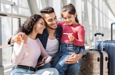 Havalimanı terminalinde uçmayı bekleyen şirin bir kızı olan mutlu bir Arap ebeveyni, yurt dışına seyahat eden üç çocuklu bir orta doğu ailesi, hatıra uçağı oyuncağı taşıyan ve gülümseyen bir çocuk.