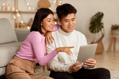 Japon erkek arkadaş ve kız arkadaş dijital tablet bilgisayar kullanarak evdeki oturma odasında yerde otururken interneti tarıyor. Birlikte Hafta sonu, Gadget ve Modern Yaşam Tarzı Konsepti