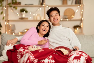 Vietnamlı çift Noel akşamı televizyon seyrediyor, film seyrediyor ve evdeki koltukta patlamış mısır yiyor. Japon Ailesi Yeni Yıl Tatilleri Boyunca Kapalı Xmas Televizyonu İzliyor