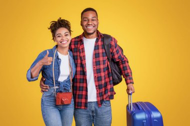 Tatile hazırım. Sarı Stüdyo 'nun arka planında duran bavul jestli siyah turist çifti. Seyahat, Seyahat, Seyahat ve Turizm Gezginleri. Boş Alanı Olan Panorama