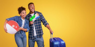 Neşeli Afrikalı turistler bavullarıyla eğlenceli pozlar veriyorlar ve sarı stüdyonun arkasında duran çocuk oyuncakları. Seyahat Keyfi, Tatil Hazırlama Konsepti