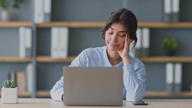 Genç bir kadın evinden aldığı online ders sırasında dizüstü bilgisayarına odaklanıyor. Eğitmen ya da öğretmen gibi görünüyor, uzaktan eğitim sağlamakla meşgul..