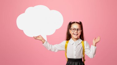 Modern okul kızı. Üniformalı neşeli çocuk pembe arka planda soyut bulutlar tutuyor.