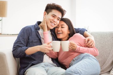 Günaydın Kahve. Asyalı kocayı ve karısını seven, sıcak içkiler içen, bardakları tutan ve evdeki koltukta kucaklaşan. Birlikte Homey Weekend 'in tadını çıkarın. Metin için Boşluk