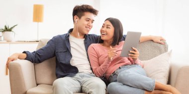 Japon Eşler Evdeki Oturma Odasında Oturarak İnternet 'te Dijital Tablet Bilgisayarı Kullanıyorlar. Kız arkadaşı ve erkek arkadaşı hafta sonunu birlikte geçiriyorlar. Modern Malzemeler ve Uygulamalar