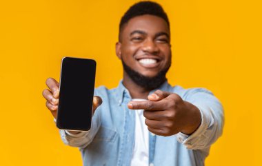 Şu uygulamayı kontrol et. Siyah ekranlı akıllı telefonu tutan ve işaret eden neşeli afro adam, boş alanı olan sarı arka plan.
