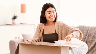 Hızlı Teslimat Servisi Konsepti. Mutlu kadın alıcı paketini aldı, karton kutuları açtı, evdeki koltukta oturdu, fotokopi çekti. Çevrimiçi alışveriş ile tatmin olan kadın