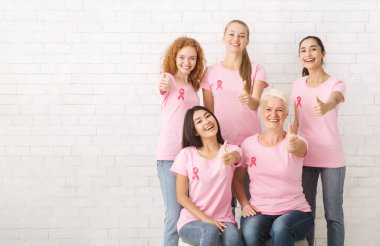 Pembe Meme Kanseri T-Shirt Kurdeleler Gesturing Thumbs-Up Beyaz Tuğla Duvar Üzerinde Poz ile Çeşitli Kadın Gönüllüler. Kopyalama Alanı