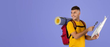 Haritası olan yakışıklı genç bir sırt çantalı ve Louise mavi arka planda güzergahını planlıyor.