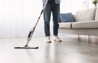 Kadının, ahşap kaplama döşemeleri, su spreyi ve doldurulabilir şişeyi temizleme maddesiyle yıkadığı yakın çekim kesimi. Ev işleri konsepti. Bulanık Arkaplan, Boş Kopyalama Boşluğu