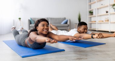 Kilit altındayken evde eğitim almış. Güçlü siyah çift spor minderleri üzerinde egzersiz yapıyor, yoga yapıyor veya evde pilates yapıyor, panorama yapıyor. Atletik Afro-Amerikan ailesi aktif bir yaşam tarzı sürdürüyor