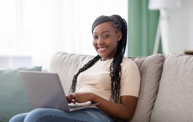 Saçları örgülü, dizüstü bilgisayarı olan, internetten video izleyen, arkadaşlarıyla sohbet eden, blog okuyan, kopyalayan Afro-Amerikan bir bayan. Covid-19 salgını sırasında yaşam tarzı