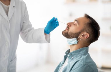 Coronavirus test prosedürü. Doktor, evdeki çubukla milenyum çocuğu için nazal PCR testi yapıyor. Genç beyaz adam koronavirüs teşhisi yapıyor. Sağlık hizmeti kavramı