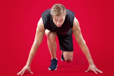 Motive olmuş genç sporcu kırmızı stüdyo arka planında koşmaya hazır. Maratona katılan spor kıyafeti içinde atletizm milenyumu koşucusu. Etkin yaşam tarzı kavramı