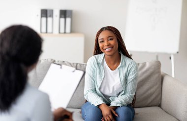Başarılı bir terapi. Genç bayan müvekkil psikologla görüşüyor. Klinikte profesyonel yardıma minnettar. Mutlu siyah bayan psikoterapistiyle konuşuyor, duygusal problemleri çözüyor.