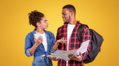 Siyahi bir çift, Tatil Planlama, Akıllı Telefon ve Turist Haritası Bekleme, Sarı Stüdyo Arkaplan 'da duruyor. Seyahat Gezme Sorunları Kavramı