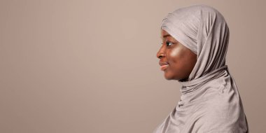 Türbanlı siyahi kadının profil portresi stüdyodaki ışık arkaplanından fotokopi odasına bakıyor. Yandan gülümseyen Afrikalı Müslüman kadının türbanlı, panorama