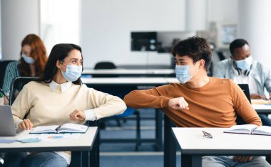 Dirsek çarpması. Sınıfta birbirini selamlayan tek kullanımlık ameliyat maskeleri takan çok ırklı genç öğrenciler. Erkek ve kadın birbirine dokunmaktan, lisede çalışmaktan, masada oturmaktan kaçınır.