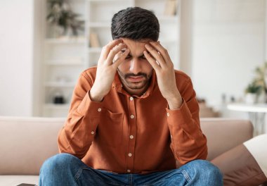 Genç Ortadoğulu adam yorucu bir günün ardından baş ağrısı çekiyor. Evdeki koltukta oturuyor, baş şakaklarına masaj yapıyor. Güçlü migreni var, yorgun, üzgün ve stresli.