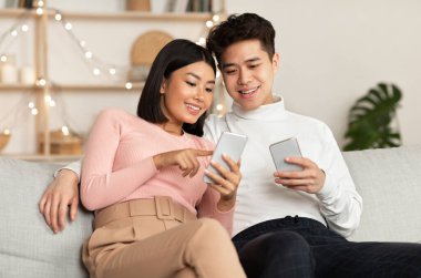 Koreli eşler cep telefonlarını internet taraması ve evdeki koltukta oturan uygulamaları tavsiye ediyor. Haftasonu Birlikte Akşam Geçiren Akıllı Telefonlu Çift.