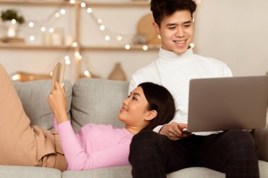 Çinli çift laptopta film izleyip hafta sonunu evde kitap okuyarak geçiriyorlar. Asyalı erkek arkadaş ve kız arkadaş, kapalı mekanda güzel bir akşam geçiriyorlar. Aile Eğlencesi Konsepti