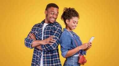 Afro-Amerikalı koca, tatilde arkadaşlarıyla sohbet ederken sarı stüdyonun arka planında karısına gizlice bakıyor. Merak, İletişim, Metin Mesajları Kavramı