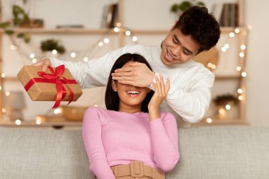 Noel hediyesi. Koreli koca, karısına Xmas hediye ediyor, gözlerini kapatıyor, tatilini evde koltukta oturarak kutluyor. Doğum günü ve Yeni Yıl Hediyeleri ve Kutlama Konsepti