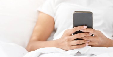 Harika bir teklif ve mesaj, uygulama, reklam, kişisel izolasyon sırasında online sohbet. Mutlu Milenyum tatlı Afro-Amerikan bayan akıllı telefonuyla yatakta, rahat yatak odasında, seçici bir odak, kırpılmış