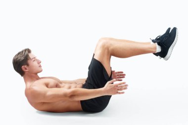 Gömleksiz güçlü bir adamın karın kasları egzersizi yapması, vücut kaslarını ışık stüdyosu arka planında çalıştırması. Yakışıklı milenyum sporcusu çıplak göğüs ve boy portresiyle çalışıyor.