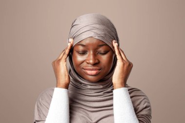 Baş ağrısı konsepti. Başörtüsü içinde üzgün bir Müslüman kadın migren ağrısı çekiyor, şakaklarına dokunuyor, Afrikalı İslami Kadın stüdyoda poz verirken rahatsız hissediyor, Boşluğu Kopyala