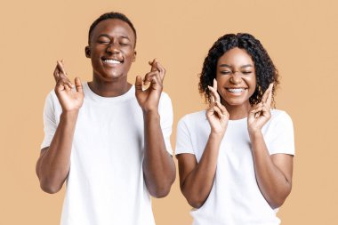 Sevgi dolu bir dilek. Gözleri kapalı, parmakları çapraz sarı, stüdyo geçmişi sarı, panorama olan neşeli Afro-Amerikan çift. Duygusal siyah erkek ve kadın iyilik için dua ediyorlar.