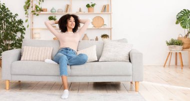 Huzur ve sessizlik, temizlik ve ev işlerinden sonra evde dinlenmek ve dinlenmek. Bin yıllık Afro-Amerikan kadını rahat rahat koltukta oturuyor ve oturma odasındaki boşluğa bakıyor.