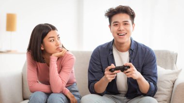 Japon kız arkadaşının evde koltukta oturup video oyunu oynarken çocuksu erkek arkadaşına bakmasından memnun değil. Erkek Duygusuzluğu, Oyun Bağımlılığı. Bilgisayar Oyunları ve Zaman israfı Kavramı