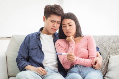 Hüsrana uğramış Asyalı Çiftin Negatif Hamilelik Testi Evdeki Koltukta Kucaklaşan Kısırlık Mücadelesi. Çinli eşler ebeveyn olmayı hayal ediyor. Çocuk Doğumu Konsepti