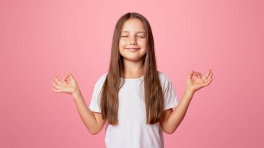 Sakinleştirici, meditasyon, ruh hali. Gözleri kapalı küçük çocuk yoga yapıyor, pembe arka planda izole edilmiş, stüdyo çekimlerinde.