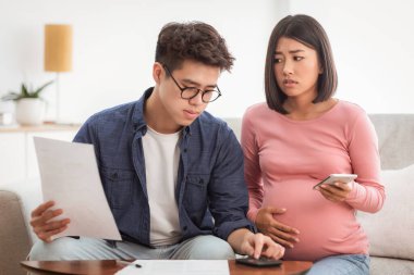 Finansal kriz. Mutsuz Çinli eşler faturaları hesaplıyor ve evdeki koltukta oturan borçları ödeyemiyor. Asyalı bir ailenin geçinmek için parası yok.