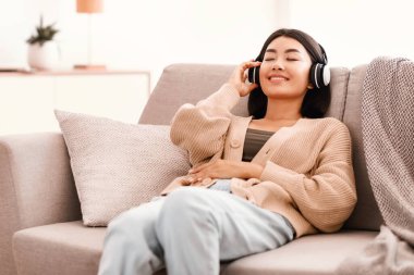 - Boş zaman. Oturma odasındaki kanepede dinlenen, müzik dinleyen Asyalı kadının portresi. Milenyum kadını en sevdiği şarkıyı seviyor, kanepeye uzanıyor ve kablosuz kulaklığa dokunuyor, kopyalama alanı.